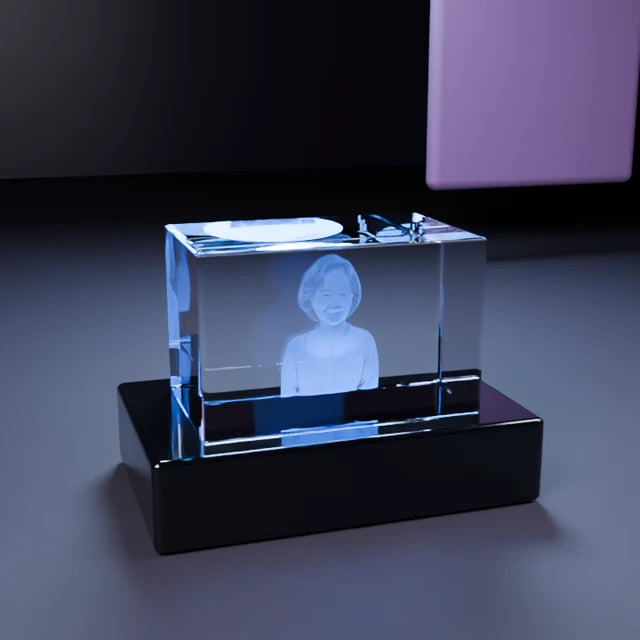 A personalized crystal glowing on its LED base beside a wrapped gift in a warm home