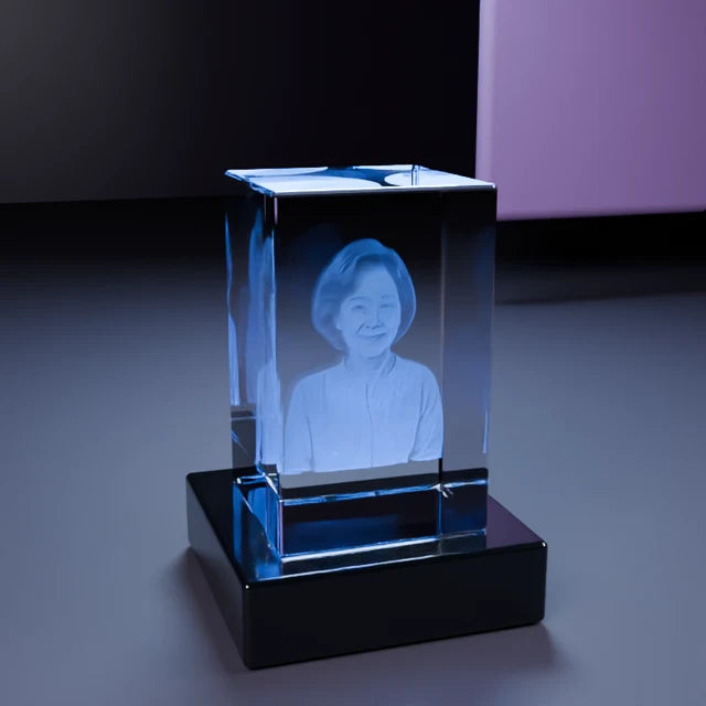 A personalized crystal glowing on its LED base beside a wrapped gift in a warm home